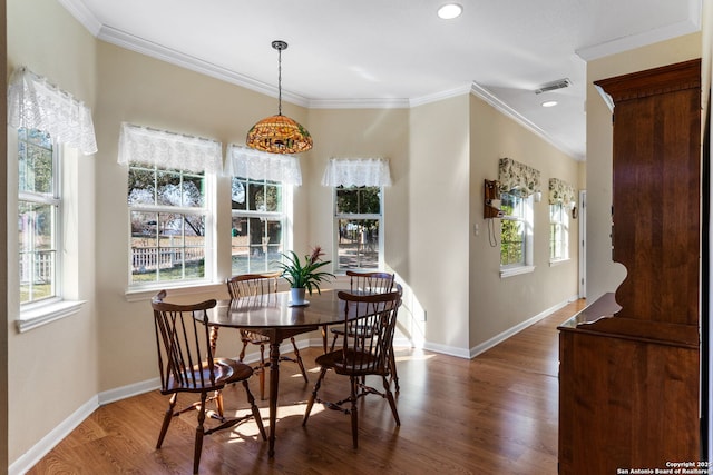 dining area featuring wood-type flooring, ornamental molding, and plenty of natural light