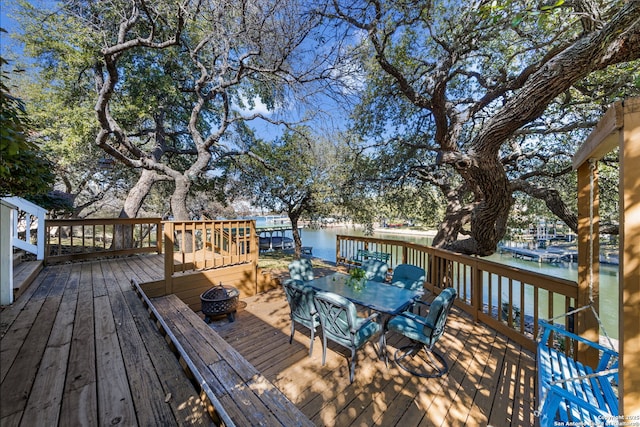 deck with an outdoor fire pit and a water view