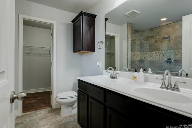 bathroom featuring vanity, toilet, and a tile shower