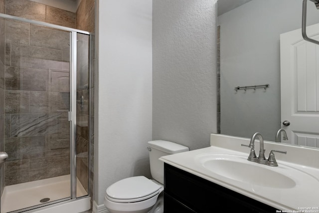 bathroom featuring vanity, a shower with shower door, and toilet