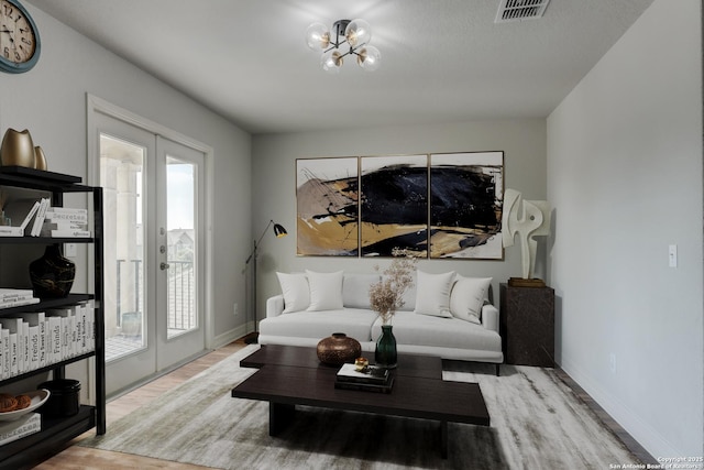 living room featuring a notable chandelier, light wood-type flooring, and french doors