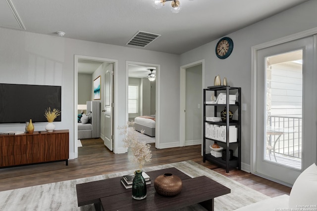 living room featuring dark wood-type flooring and ceiling fan