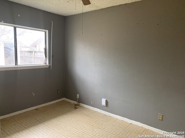 empty room with ceiling fan and a textured ceiling