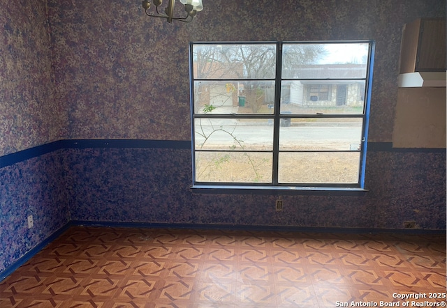 empty room featuring parquet floors and a chandelier