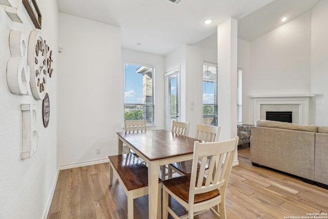 dining room featuring light wood-style flooring, a fireplace, baseboards, and recessed lighting