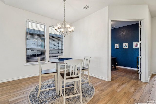 dining area with light wood finished floors, visible vents, baseboards, and a notable chandelier