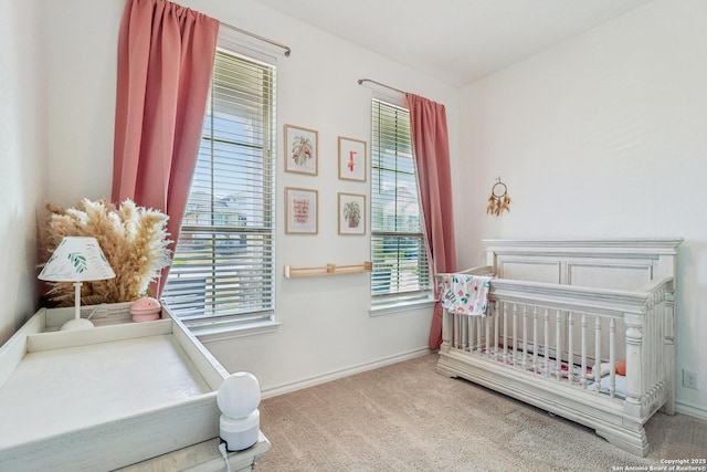 carpeted bedroom featuring a crib and baseboards