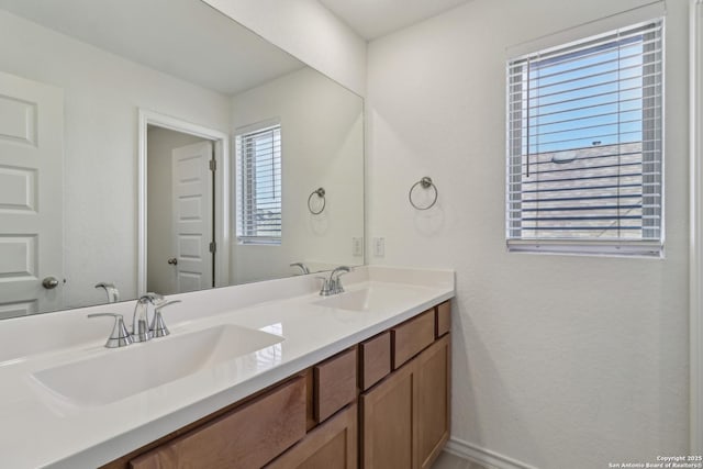 full bath with double vanity, baseboards, and a sink