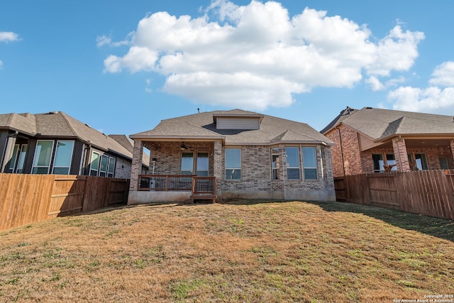 rear view of house featuring a fenced backyard, a ceiling fan, a lawn, and brick siding