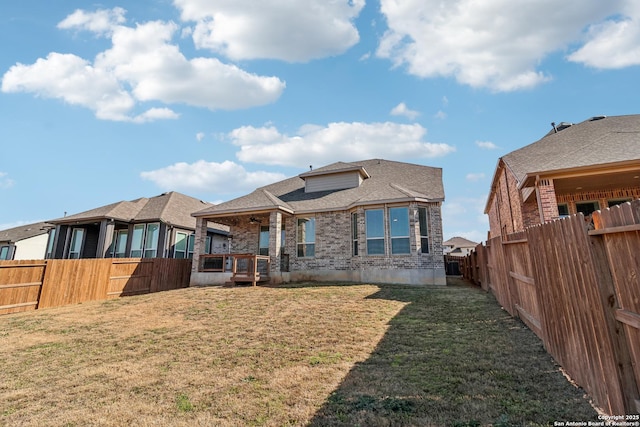 back of property featuring a fenced backyard, a lawn, and brick siding