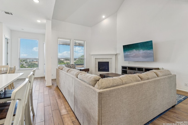 living area with a fireplace, light wood finished floors, recessed lighting, visible vents, and baseboards