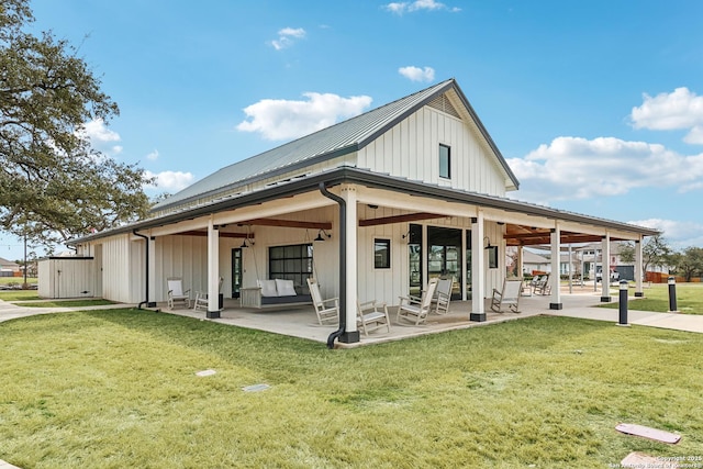 back of house featuring metal roof, board and batten siding, a patio area, and a lawn