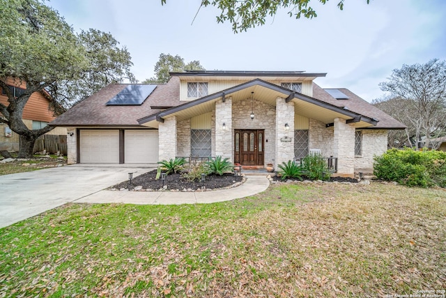 view of front of property with french doors, a garage, a front yard, and solar panels