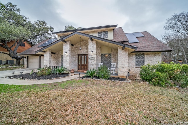 view of front of home with a garage, a front lawn, and solar panels