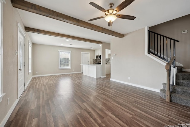 unfurnished living room featuring beamed ceiling, ceiling fan, and dark hardwood / wood-style floors