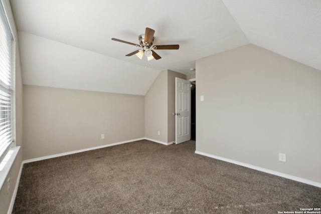 additional living space featuring vaulted ceiling, a healthy amount of sunlight, ceiling fan, and dark carpet