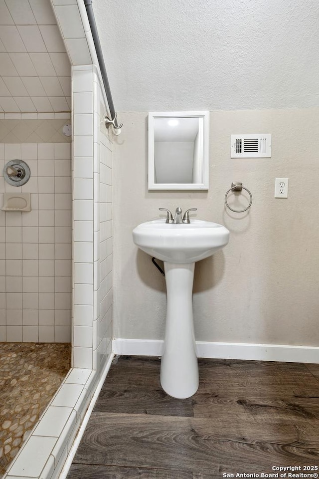 bathroom featuring a tile shower, hardwood / wood-style floors, and a textured ceiling