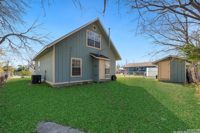 rear view of house featuring a yard, central AC, and a storage unit