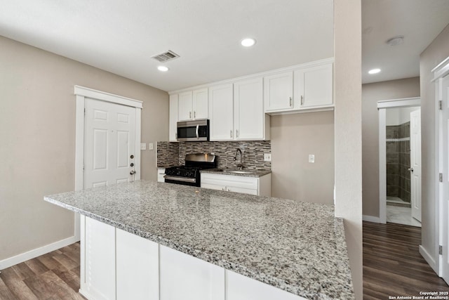 kitchen featuring black gas range, white cabinetry, light stone countertops, and decorative backsplash