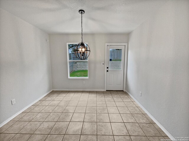 unfurnished dining area with a chandelier and a textured ceiling