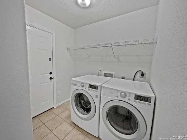 washroom featuring washer and clothes dryer, a textured ceiling, and light tile patterned floors