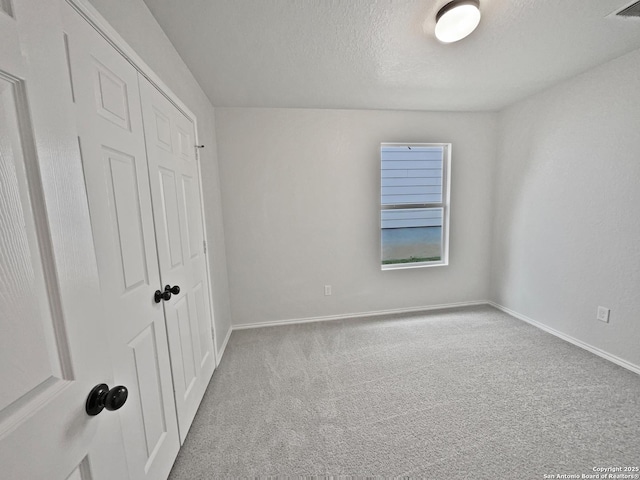 unfurnished bedroom with light colored carpet, a closet, and a textured ceiling