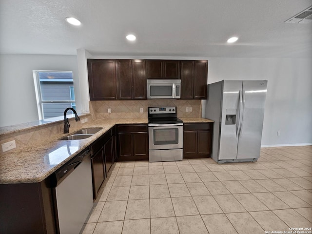 kitchen featuring light tile patterned flooring, sink, stainless steel appliances, light stone countertops, and decorative backsplash