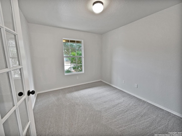 carpeted empty room featuring a textured ceiling