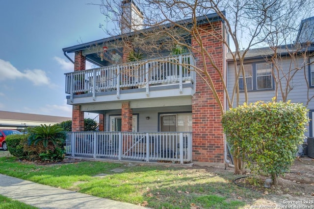 view of front facade featuring a balcony and a front lawn