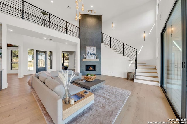 living room with a towering ceiling, a fireplace, and light wood-type flooring