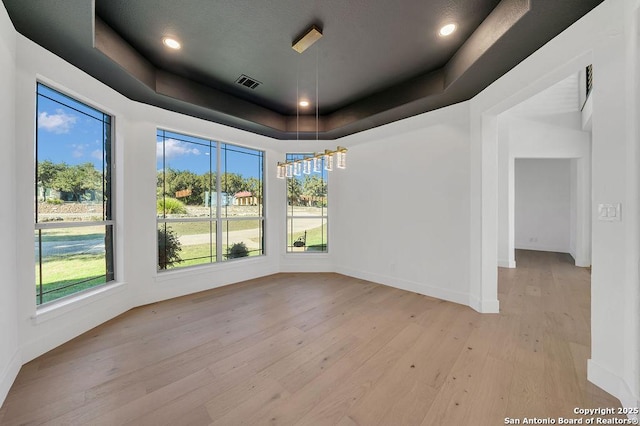 empty room featuring light hardwood / wood-style flooring and a tray ceiling