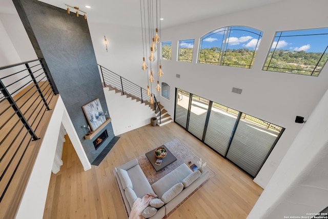 living room with a healthy amount of sunlight, light hardwood / wood-style flooring, and a high ceiling