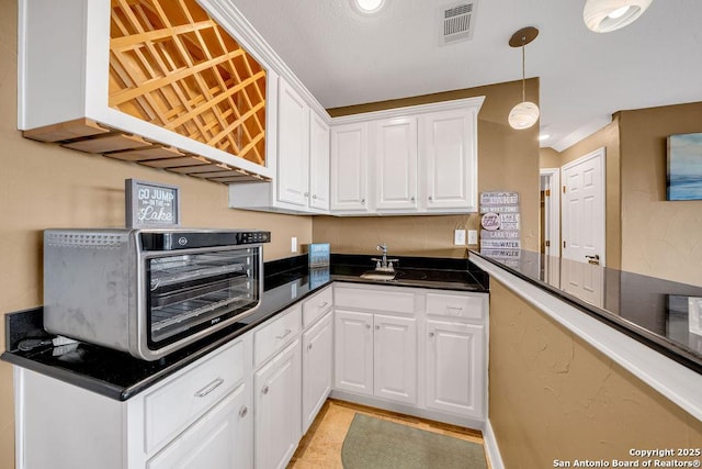 kitchen featuring pendant lighting, kitchen peninsula, and white cabinets