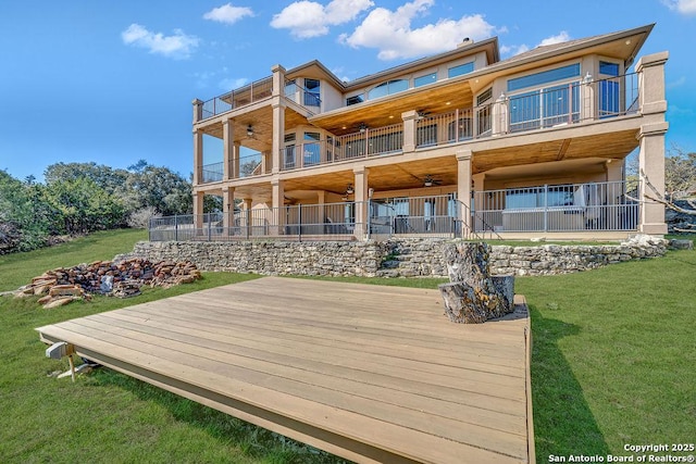 back of property with ceiling fan, a lawn, and a balcony