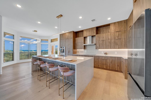 kitchen featuring decorative light fixtures, sink, wall chimney exhaust hood, black electric cooktop, and a spacious island