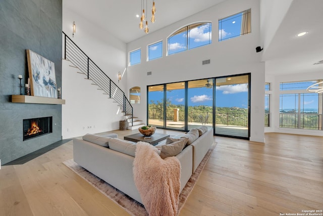 living room with a tiled fireplace, a notable chandelier, plenty of natural light, and light wood-type flooring