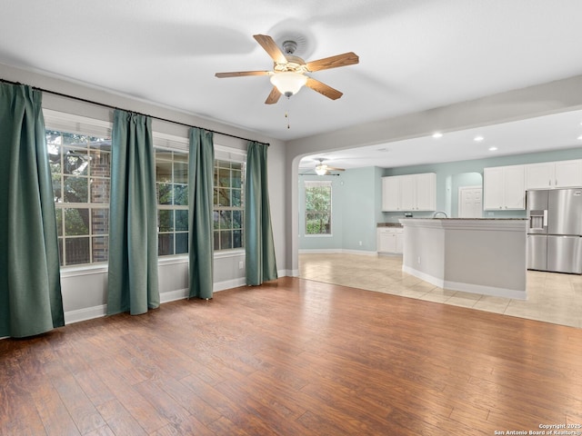 unfurnished living room featuring a wealth of natural light, light hardwood / wood-style floors, and ceiling fan