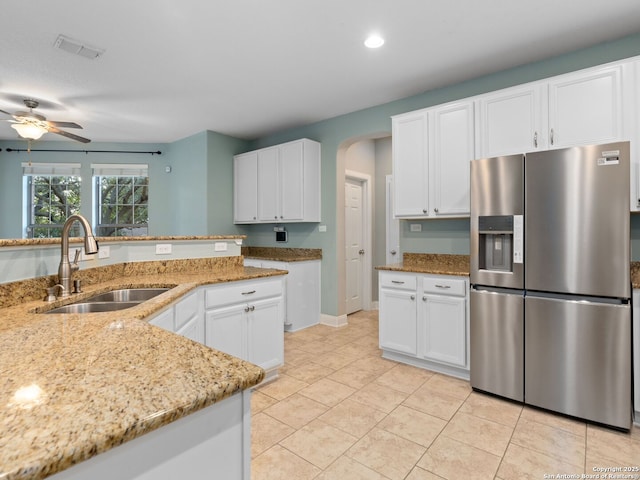 kitchen featuring white cabinetry, sink, stainless steel fridge with ice dispenser, and light stone counters