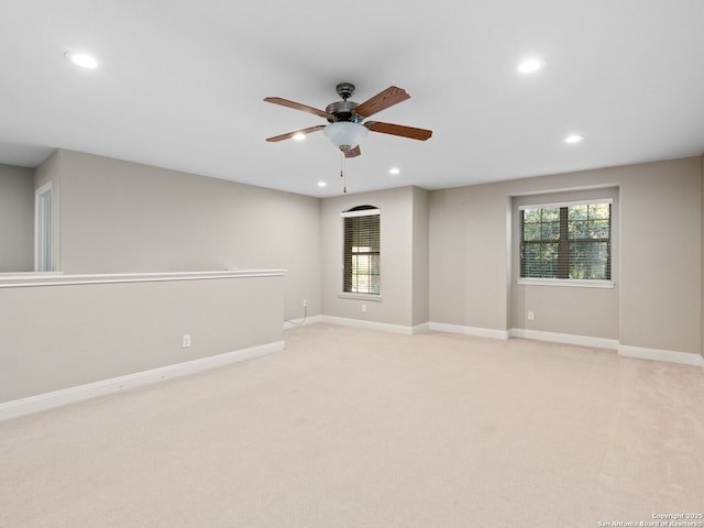 empty room featuring ceiling fan, light colored carpet, and a healthy amount of sunlight