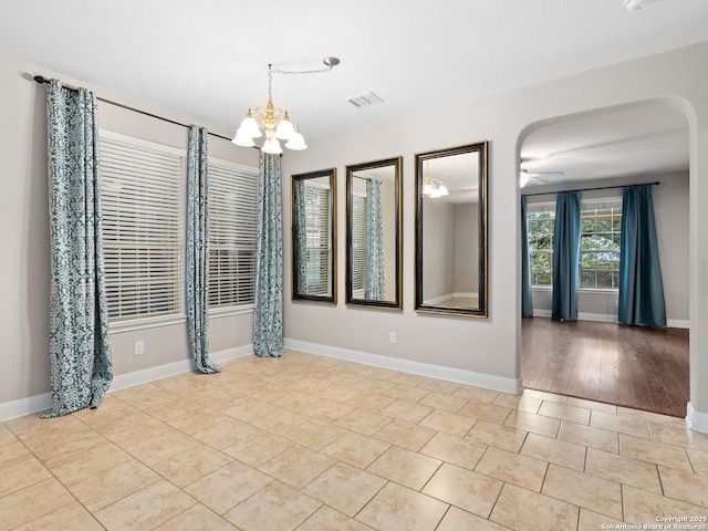 empty room featuring ceiling fan with notable chandelier and light tile patterned floors