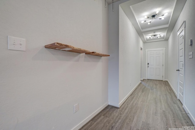 corridor featuring light hardwood / wood-style flooring and a raised ceiling