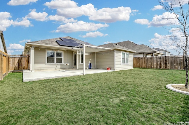 back of property with a yard, a patio, and solar panels