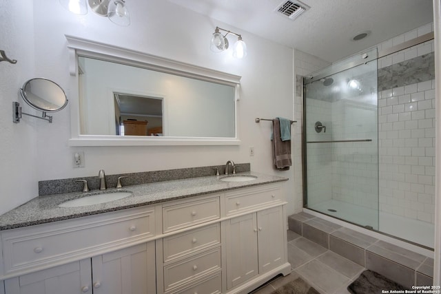 bathroom featuring vanity, a shower with door, and a textured ceiling