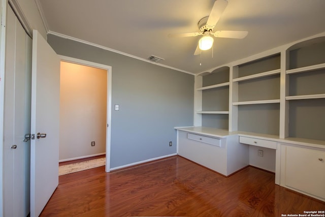 unfurnished office with hardwood / wood-style flooring, ornamental molding, built in desk, and ceiling fan