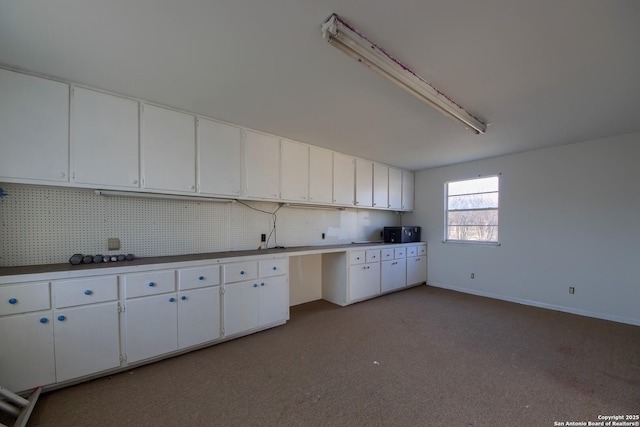 kitchen with tasteful backsplash, light colored carpet, and white cabinets