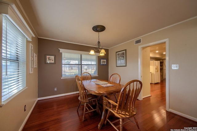 dining room with ornamental molding, dark hardwood / wood-style floors, and a notable chandelier