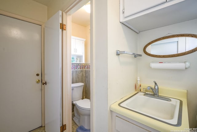 bathroom with sink, tile walls, and toilet