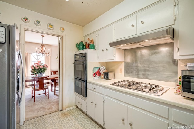 kitchen featuring an inviting chandelier, light carpet, pendant lighting, stainless steel appliances, and white cabinets