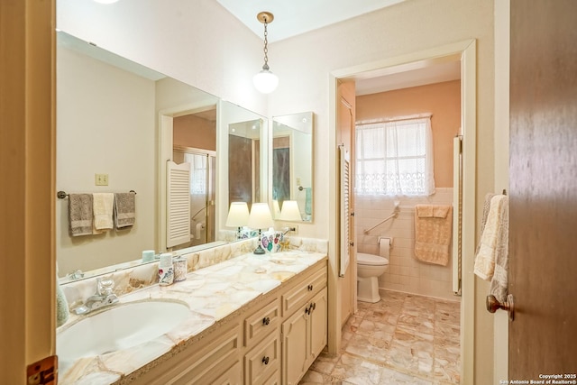 bathroom featuring vanity, toilet, and tile walls