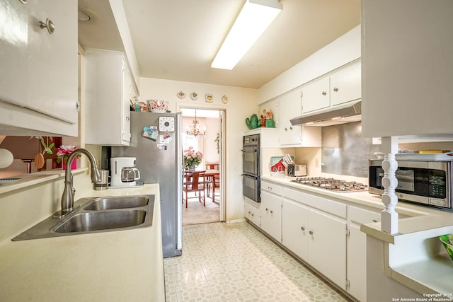 kitchen featuring sink, white cabinetry, stainless steel appliances, tasteful backsplash, and a notable chandelier